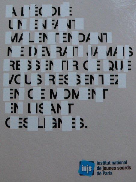Affiche sur laquelle la moitié des lettre est cachée et lisible difficilement du premier coup. Le texte suivant est "à l'école un enfant malentendant ne devrait jamais ressentir ce que vous ressentez en ce moment en lisant ces lignes". Affiche de l'Institut National des Jeunes Sourds de Paris