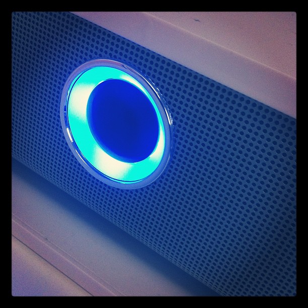 Enceinte de musique allumée, on voit le bouton entouré d'une lumière bleue