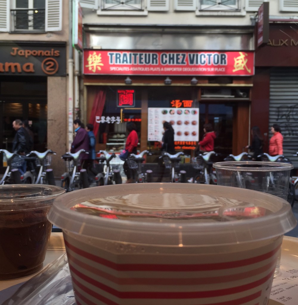En premier plan, on voit mon déjeuner derrière la vitrine du restaurant et en arrière plan la facade du Traiteur Victor