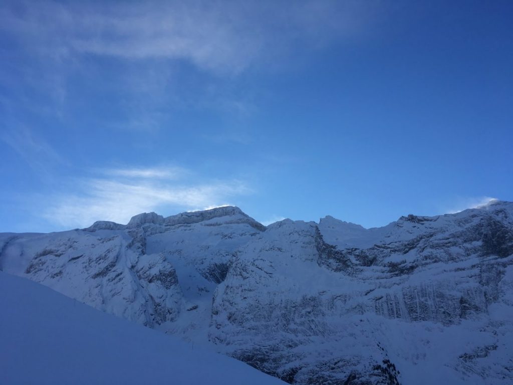 Horizon de montagne enneigée avec un ciel bleu, la neige vole aux cîmes des montagnes