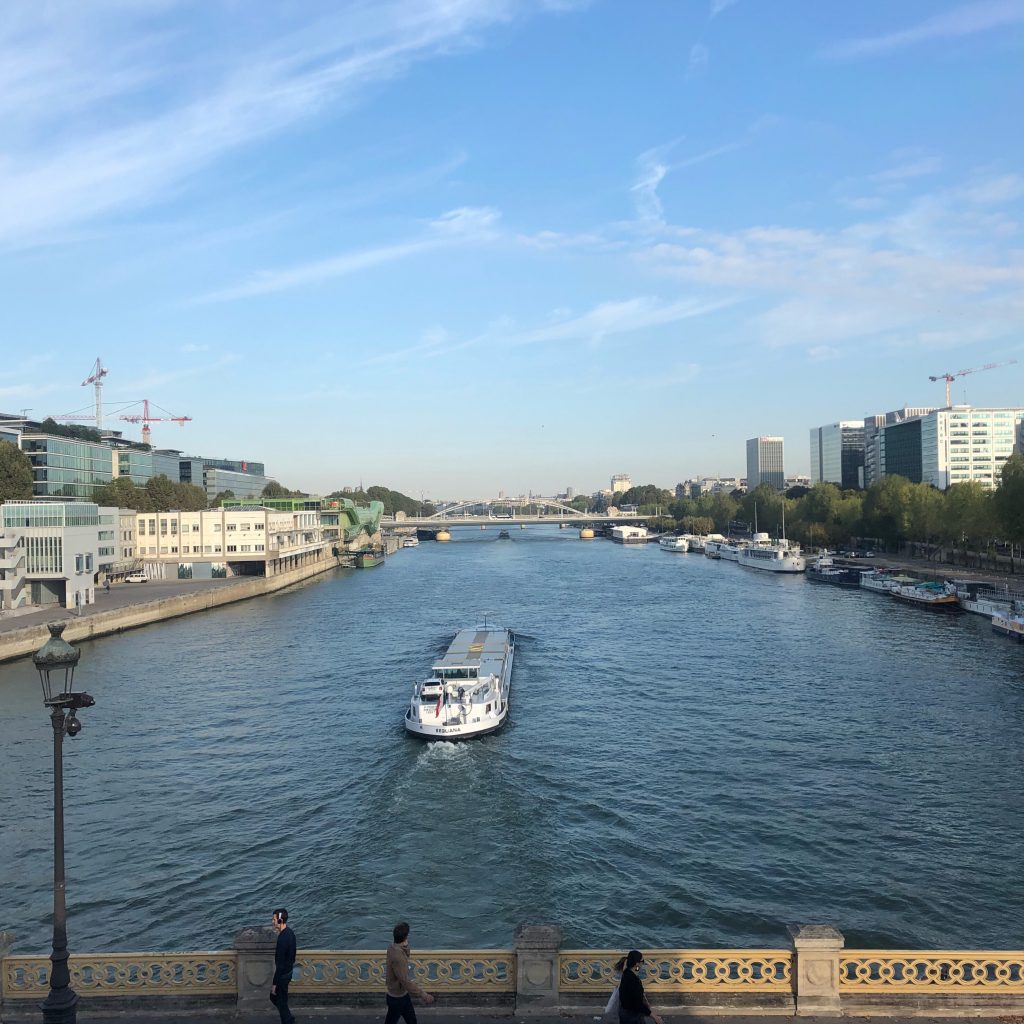 Vue du pont de Bercy, une péniche sur la Seine, un ciel bleu parsemé de nuages.