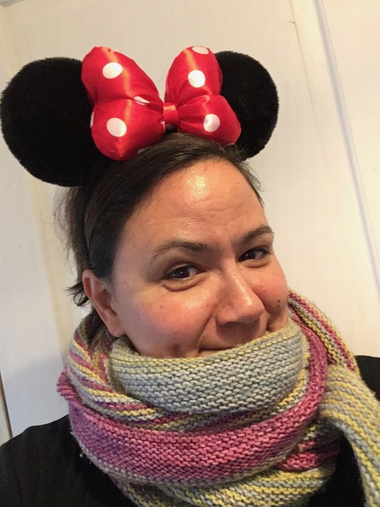 Sophie emmitouflée dans un châle avec un regard malicieux et des oreilles noires de Minnie assorties d'un gros nœud rouge à pois.