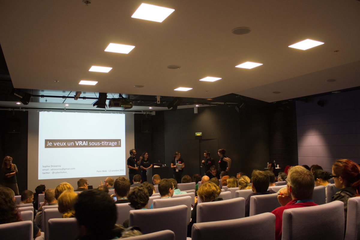 Moi en train de présenter la conférence devant une salle remplie à Paris Web. Sur l'écran est indiqué le titre suivant : "je veux un vrai sous-titrage !"