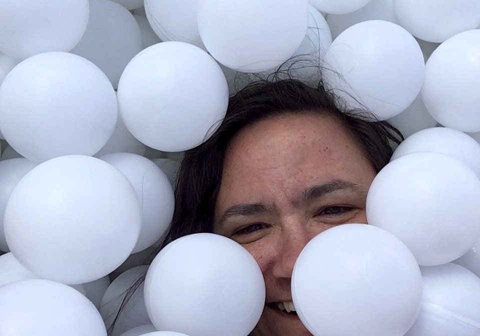Sophie cachée par des balles en plastique blanches