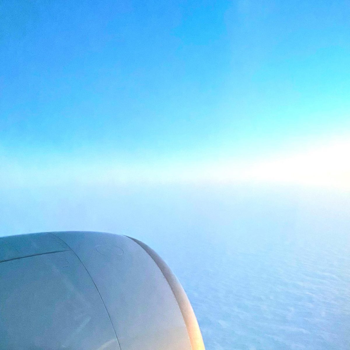 Morceau d'hublot d'avion avec un horizon donnant sur un ciel bleu et les nuages blancs